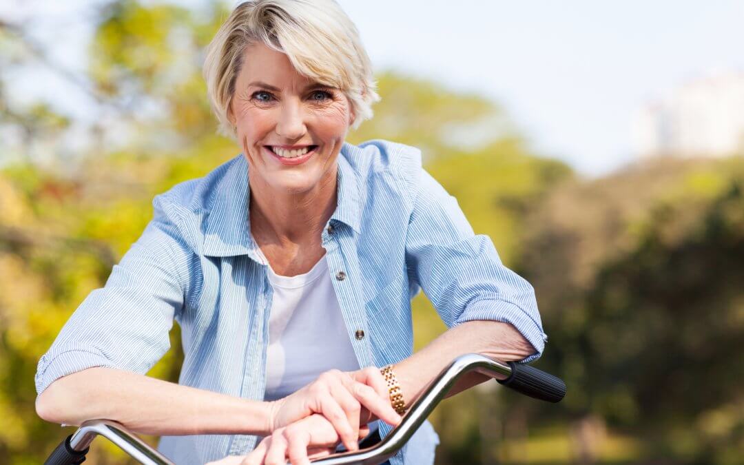 Blonde vrouw op een fiets die lacht omdat ze geen aandrang of overactieve blaas meer heeft