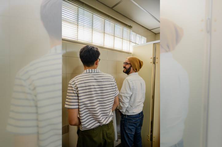 Foto van twee plassende mannen in een openbaar toilet