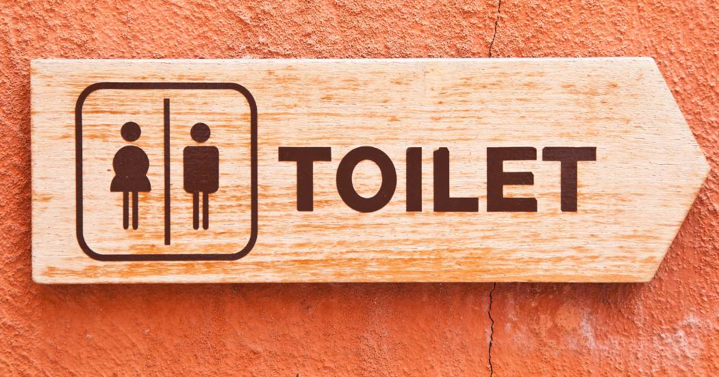Toiletbordje met man en vrouw iconen; relatie met urineverlies of incontinentie.