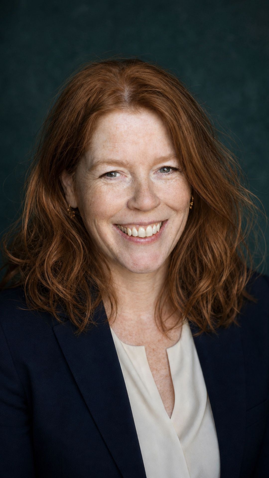 dr. Erna Beers, arts en seksuoloog Portretfoto van dr. Erna Beers, gepromoveerd arts en seksuoloog, lachend voor een donkergroene achtergrond.